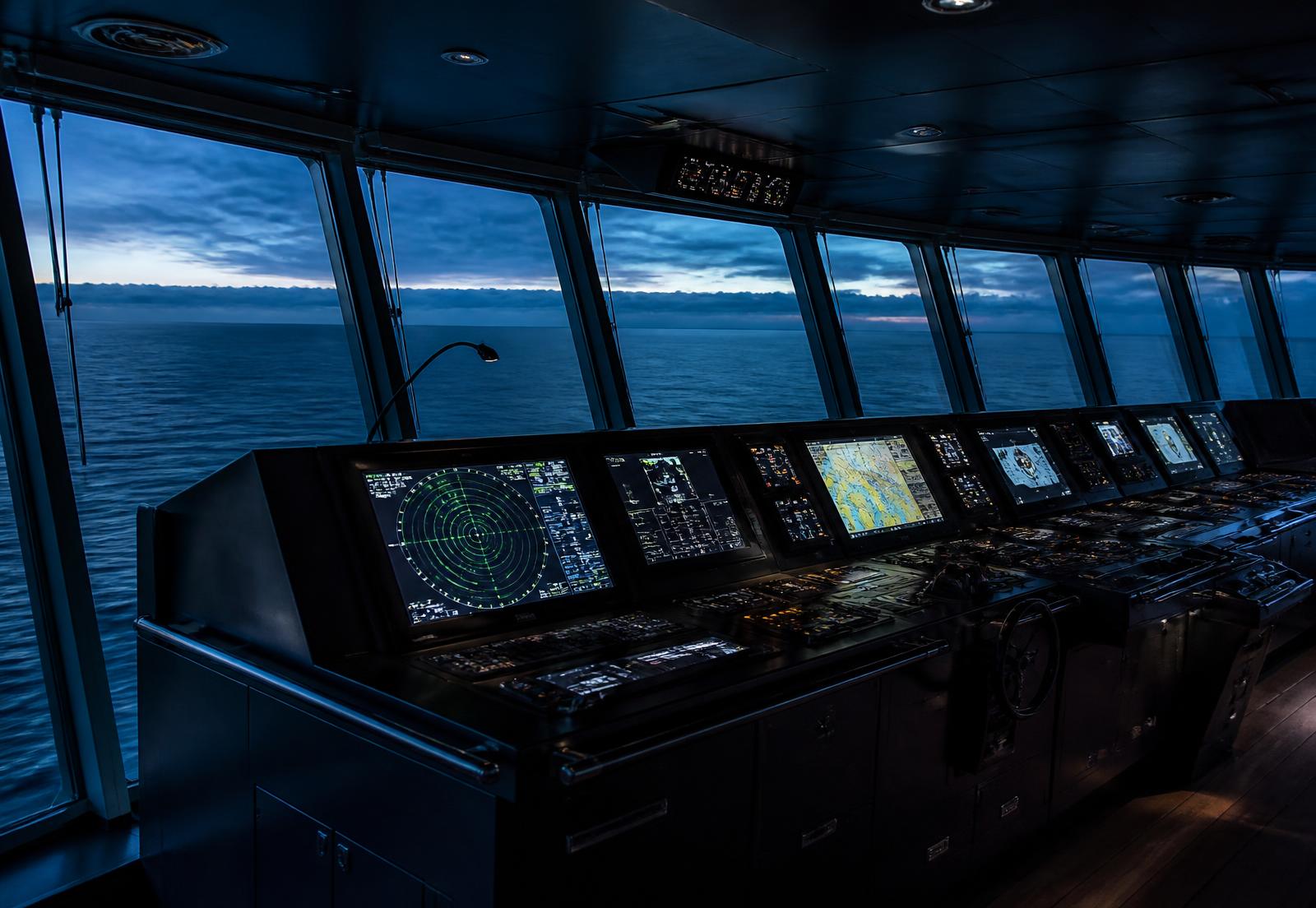Ship bridge with navigation and radar displays at blue hour
